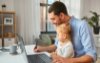 Dad with young daughter in his lap sitting at work desk