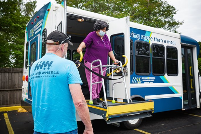 Woman with a walker gets off of a bus via its movable ramp