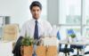 Office worker holding all of his work belongings in a cardboard box